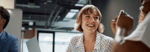 A woman in a polka dot shirt smiling amongst coworkers